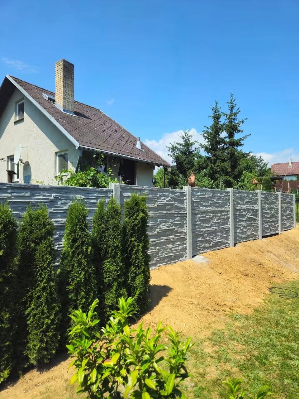 Šedý betonový plot s kamenným dekorem před rodinným domem