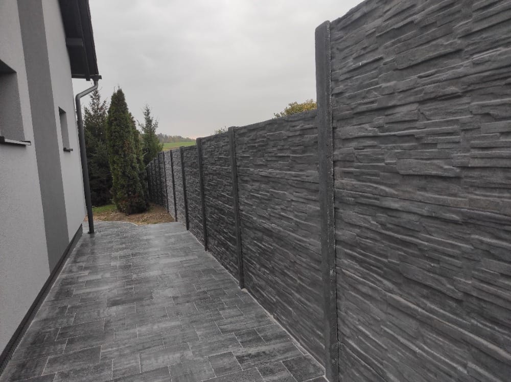 Tmavě antracitový betonový plot vedle moderního domu